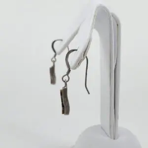 Silver earrings on a white display stand.