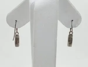 Silver dangle earrings on white stand.