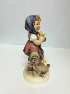 Figurine of girl with chicks and rooster.