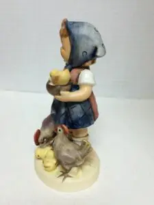 Child figurine with chicks and ducklings.