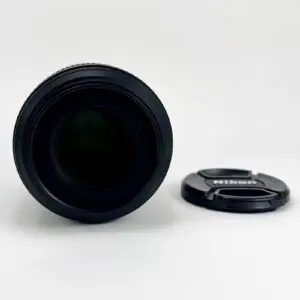 Camera lens with detached Nikon lens cap.