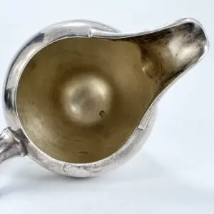 Silver jug with a wide spout opening.