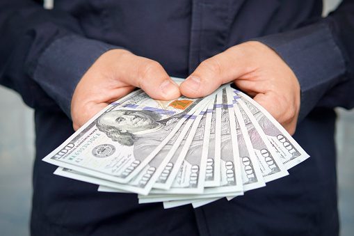 Male hands holding one hundred dollar bills