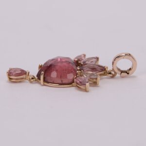 Gold pendant with pink gemstones on display.