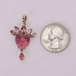 Pink gemstone pendant beside a quarter.