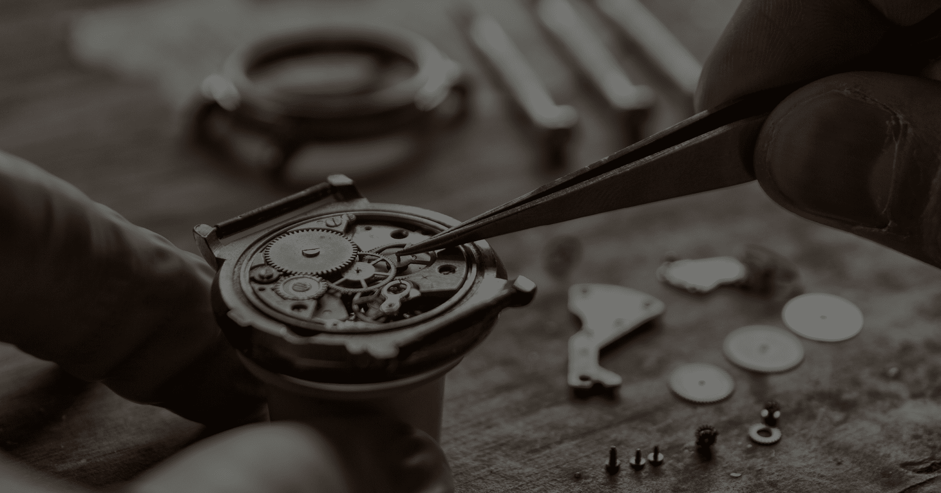 Close-up of hands using tweezers to adjust gears inside a mechanical watch. Watch parts and tools are visible in the background.