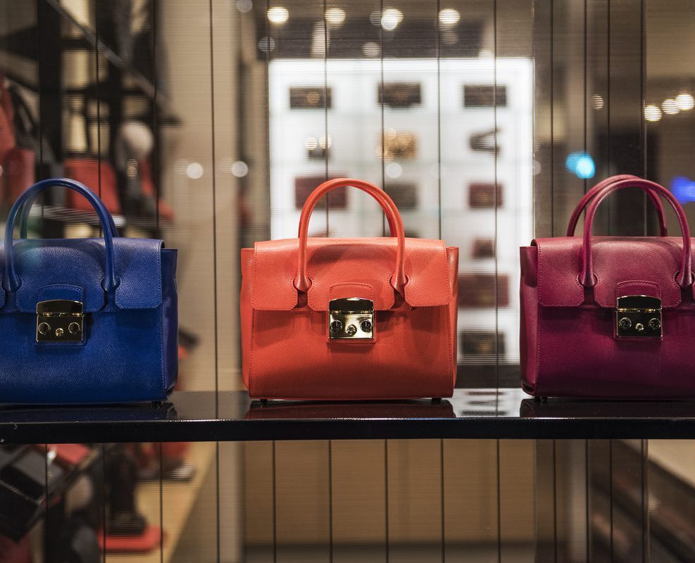 Three different colored bags are on display in a store.