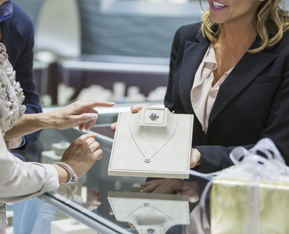A woman is holding her necklace while she 's giving it to someone else.