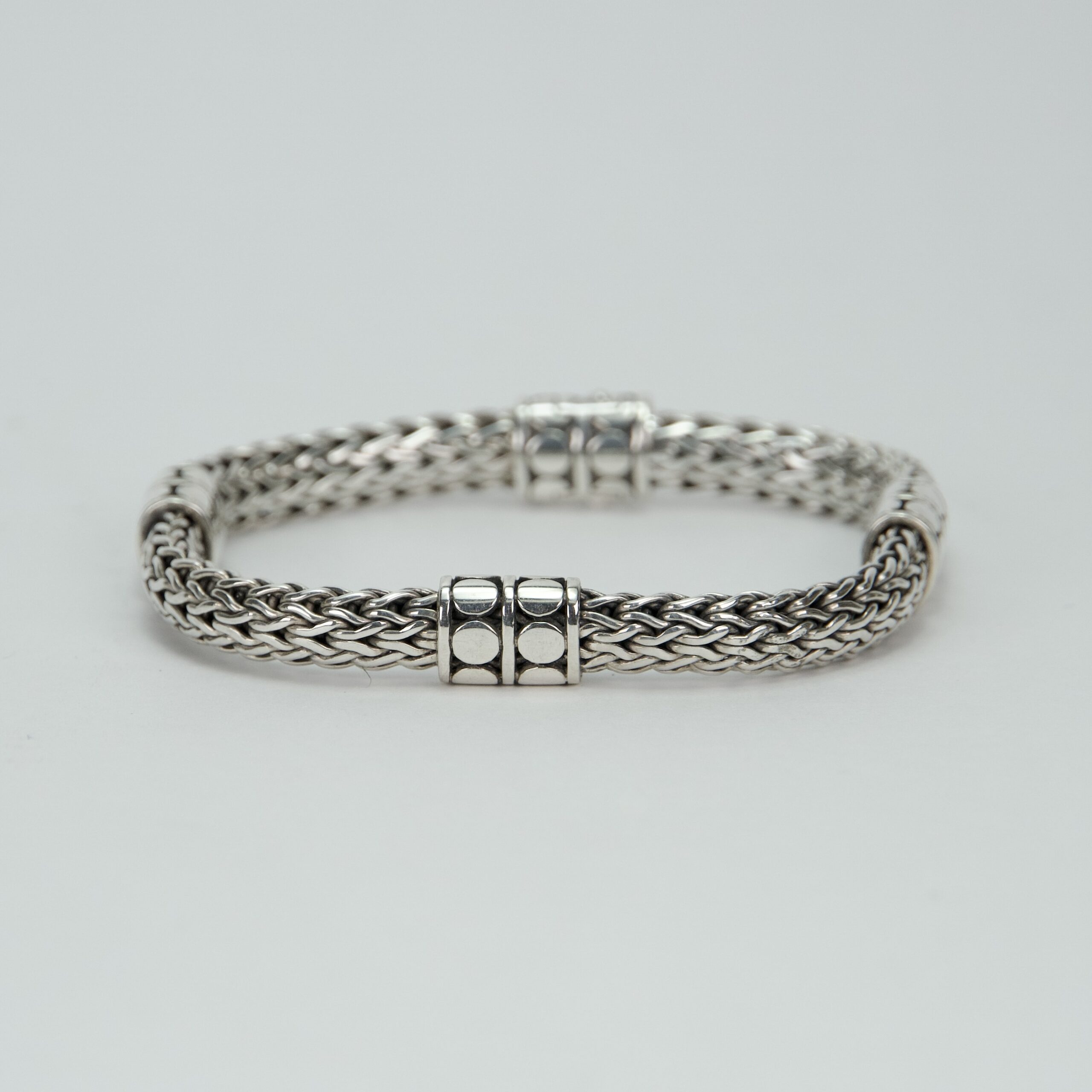 Silver woven bracelet with decorative clasps.