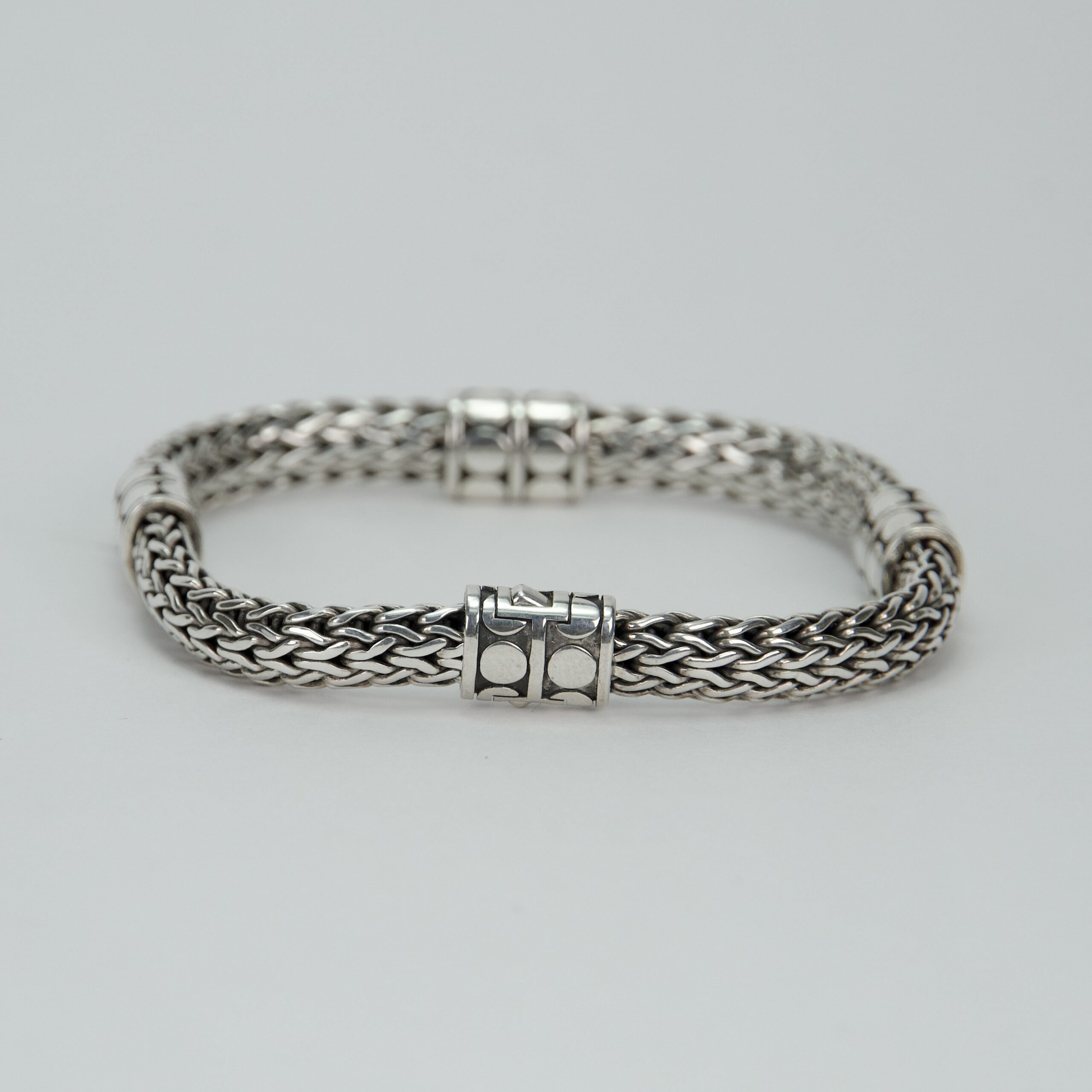 Silver woven bracelet on white background.