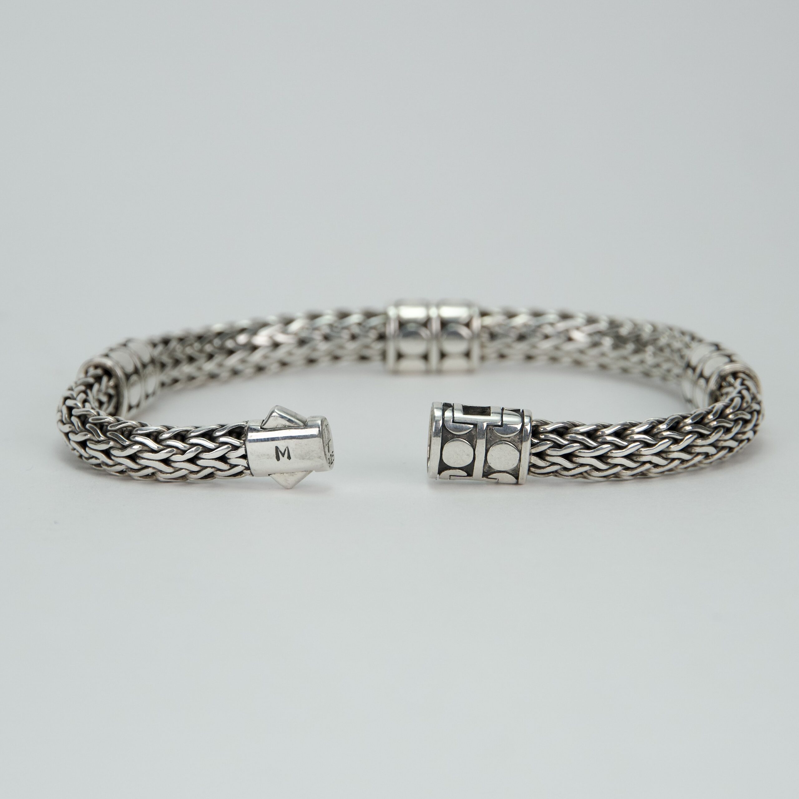Silver woven bracelet with decorative clasps.