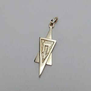 Gold pendant with geometric design and symbol.