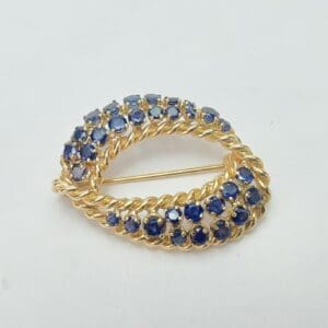 Gold brooch with blue gemstones on display.