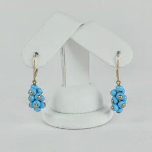 Blue beaded earrings on white display stand.