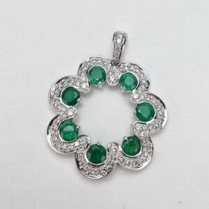 Silver flower pendant with green gemstones.