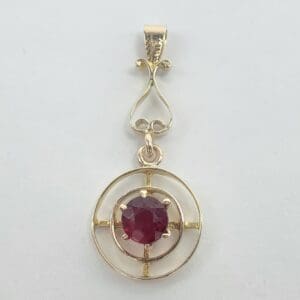 Gold pendant with a red gemstone.